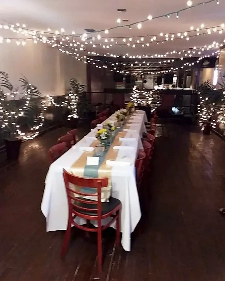 The Upper Room set for dinner under string lights